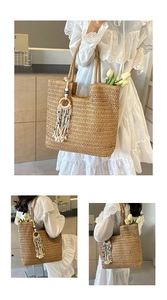 Detail of woven straw tote bag featuring tassel charm and evil eye bead decoration