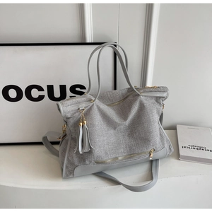 Detailed view of grey textured tote bag with tassel charm and adjustable strap