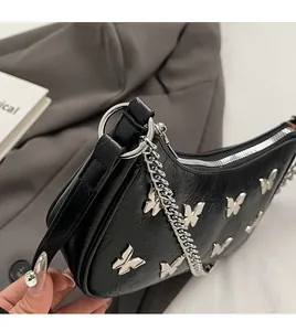 Close-up of black pleated leather bag featuring silver butterfly charms and chunky chain