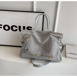Detail of silver shimmer texture large tote bag with leather tassels and gold zipper