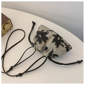 Detail of drawstring bucket bag with black floral print on thick cream canvas texture