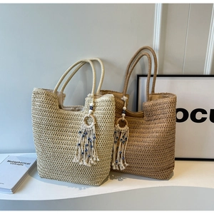Detail of woven straw tote bags with tassel charms and blue evil eye bead accents