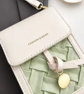 Detailed view of woven green fabric and beige leather flap on a small crossbody bag
