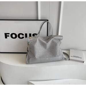 Detail of silver canvas tote bag with woven texture, leather trim and metal zipper