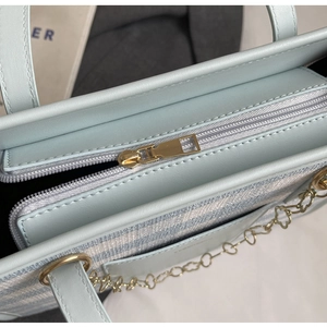 Close-up of golden zipper and heart chain detail on light blue canvas tote bag