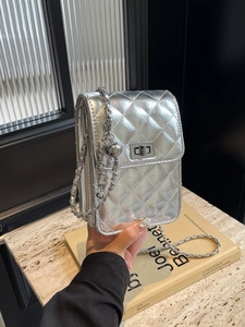 Silver quilted crossbody bag with metallic chain strap and lock on marble surface