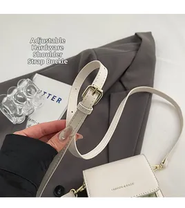 Adjustable gold metal buckle and stitching detail on cream woven small crossbody bag
