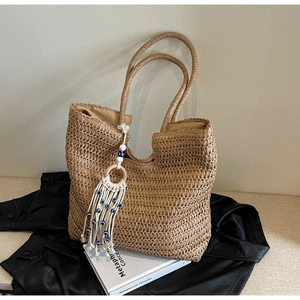 Detail of a straw tote bag with a white tassel pendant and blue evil eye beads