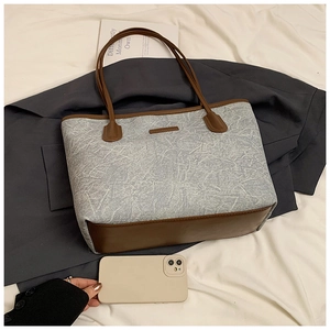 Detail of large tote bag in light blue marble texture with brown leather base and straps
