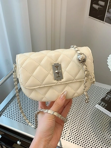 Chic cream quilted saddle bag with silver blade lock and chain strap held by hand