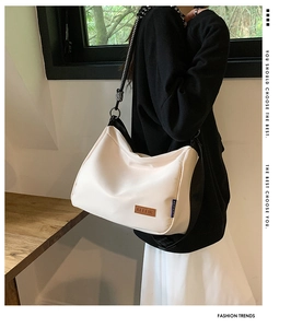 Détail du sac cabas en toile crème avec bandoulière tissée et écusson en cuir