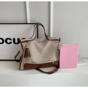 Detail of canvas and brown leather stitching with decorative tassel on a tote bag