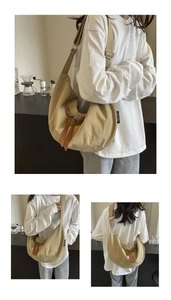 Detail of beige canvas crescent bag showing leather zipper pulls and adjustable strap
