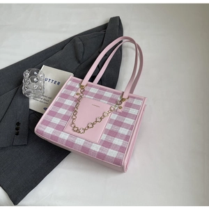Detailed close-up of pink checkered canvas tote with golden flower chain and leather patch
