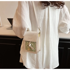 Detail of white leather crossbody bag with green woven pattern and gold metal buckle