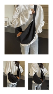 Detail view of large black canvas crescent bag featuring premium brown leather zipper pulls