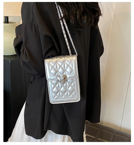 Close-up of silver quilted crossbody bag with heart buckle and metal chain strap