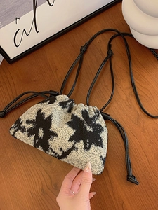Artistic cream bucket bag with black floral pattern and drawstring on wooden table