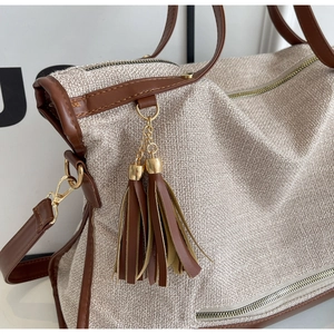 Close-up of woven canvas texture and brown leather trim on a large shoulder tote bag