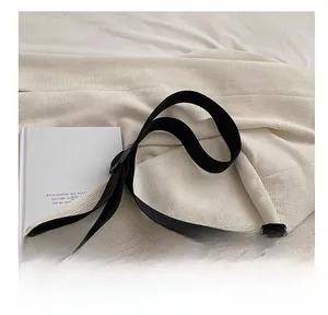 Détail de la bandoulière réglable en tissu noir avec cordon tissé décoratif sur le cabas