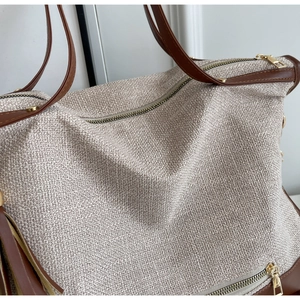 Detailed macro view of woven canvas texture with leather trim and gold zippers