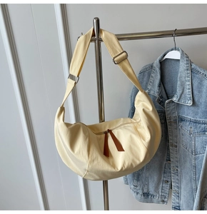 Detailed view of cream crescent bag featuring brown leather zipper pulls and adjustable strap