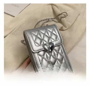 Close-up of silver quilted crossbody bag with heart-shaped metal clasp and chain