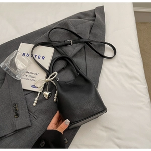Détail du sac seau noir en cuir grainé avec pendentif perle en forme de cœur chic