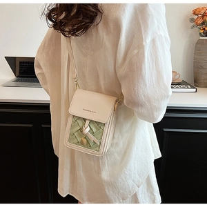 Close-up of cream and green crossbody phone bag with woven leather detail and knot charm