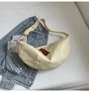 Detail view of cream crescent crossbody bag with adjustable strap in lifestyle setting