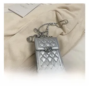 Detailed close-up of a silver quilted phone bag featuring a heart-shaped metal buckle