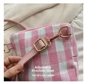 Detail of pink plaid bag showing adjustable leather strap and gold metal buckle