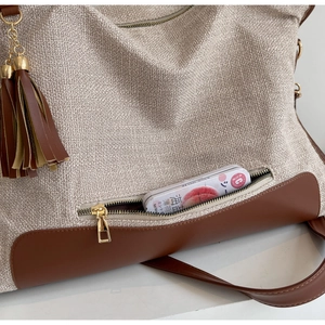 Detail of the outer zipper pocket on a canvas tote with leather trim and tassel