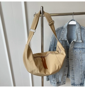 Detail of khaki canvas crescent bag with brown leather zipper pull and wide strap