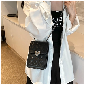 Detailed view of black quilted pattern with heart-shaped silver lock on chain bag