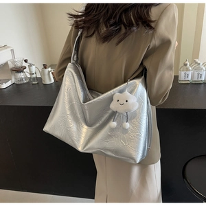 Detailed macro view of the silver metallic tote bag featuring pleated texture and plush charm