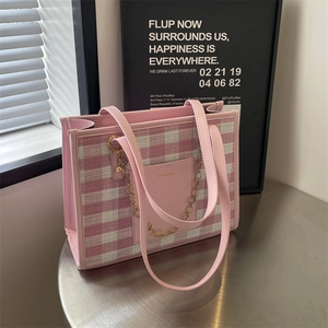 Pink plaid large tote bag with shoulder straps and gold heart charm on metal table
