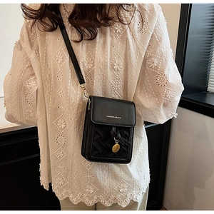 Detail of black woven crossbody bag with gold pendant and fashion print on leather