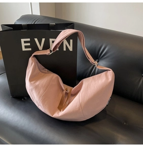 Close-up of pink crescent nylon bag texture with brown leather zipper pull and strap