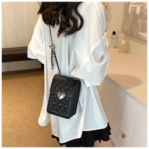 Detail of black quilted crossbody bag with silver heart lock and metal chain strap