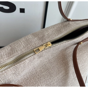 Detail of golden metal zipper and beige woven texture on large canvas tote bag