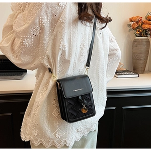 Detail of black woven crossbody bag with gold hardware and logo on white lace background