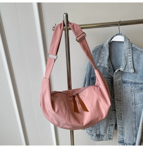 Detailed shot of pink canvas crescent bag featuring adjustable strap and silver metal hardware