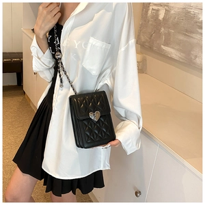 Quilted black crossbody bag with silver heart buckle and leather chain strap on model