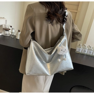 Detail of metallic silver pleated tote bag with a white plush cloud charm on a strap