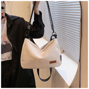Détail de la poignée en corde tressée et du logo en cuir sur le sac en toile crème