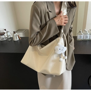 Detail of white tote bag with natural wrinkled leather texture and cute cloud charm