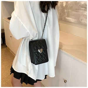 Detail of black quilted phone bag with silver heart lock and woven chain strap