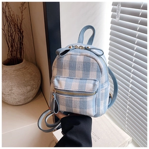 Detailed close-up of a mini blue checkered backpack featuring a decorative bow and leather strap