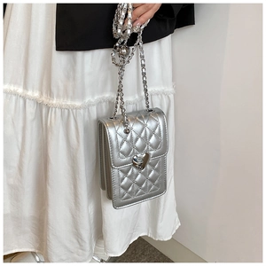 Close-up of a silver quilted mini chain bag featuring a metallic heart-shaped buckle